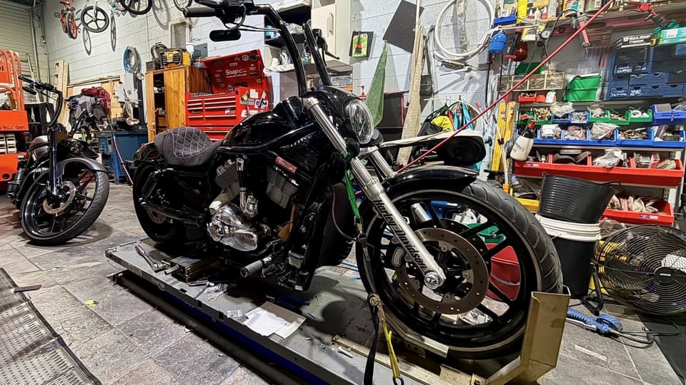 Black Harley on the lift between jobs in the workshop